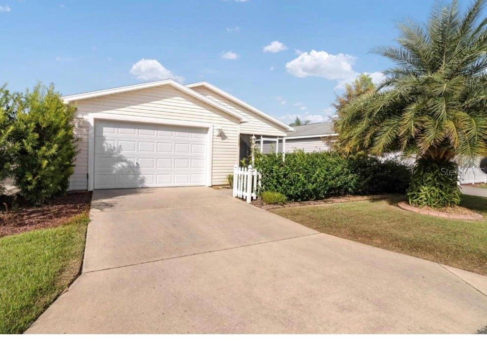 A single-story house with light siding, a one-car garage, and a palm tree in front — 1037 RIDGEVILLE ROAD, THE VILLAGES, FL