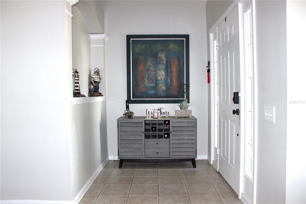 A gray entryway features a wine cabinet, wall art, and a white front door — 10228 HUNTERS HAVEN BOULEVARD, RIVERVIEW, FL