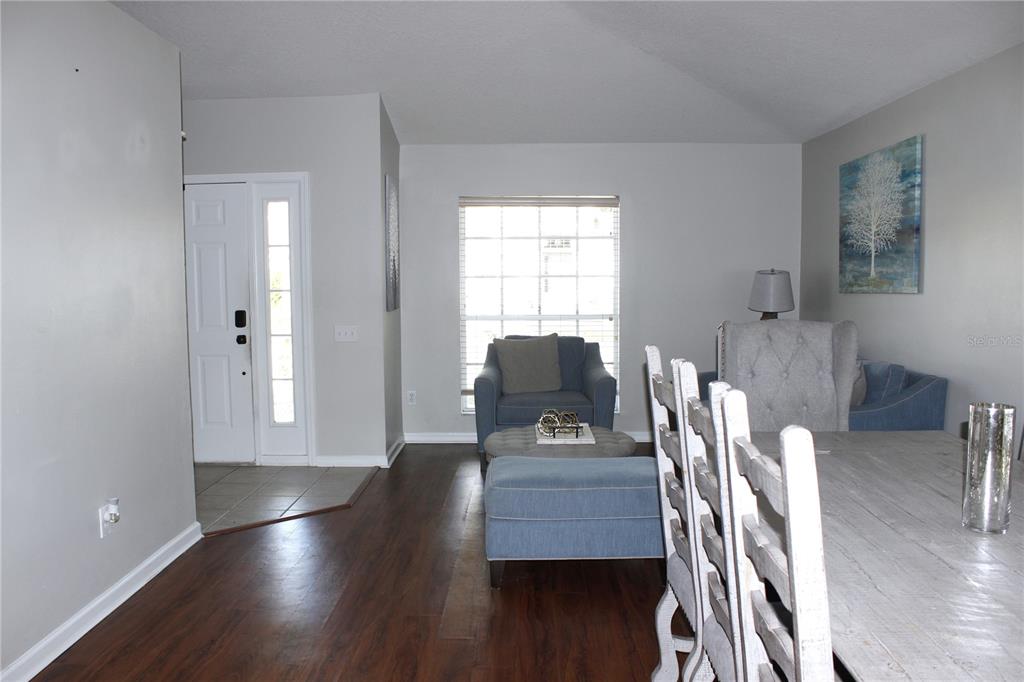 A dining area with a wooden table leads into a living space with blue furniture — 10228 HUNTERS HAVEN BOULEVARD, RIVERVIEW, FL