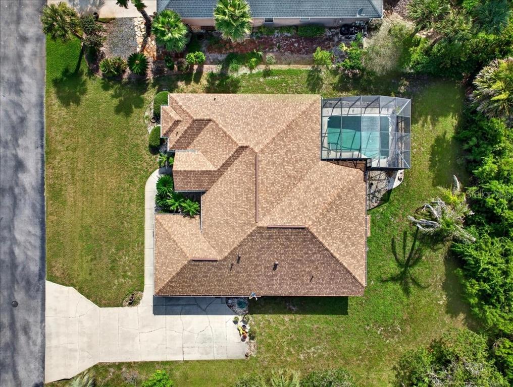An aerial view shows a house with a brown shingled roof and a screened-in pool — 10 BEACHSIDE DRIVE, PALM COAST, FL