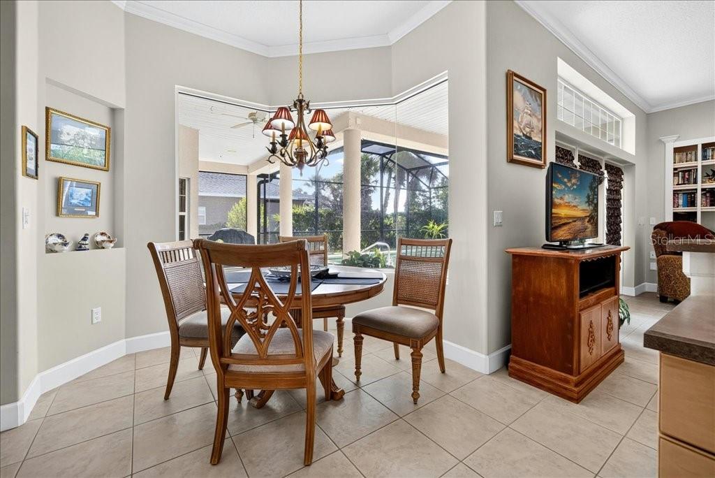 A dining area features a round table, four chairs, a chandelier, and a view of a lanai — 10 BEACHSIDE DRIVE, PALM COAST, FL