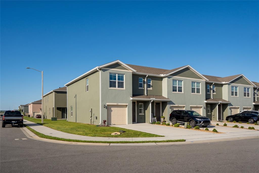A row of two-story townhouses with attached garages and driveways under a clear blue sky — 2331 GIFFORD DRIVE, DAVENPORT, FL