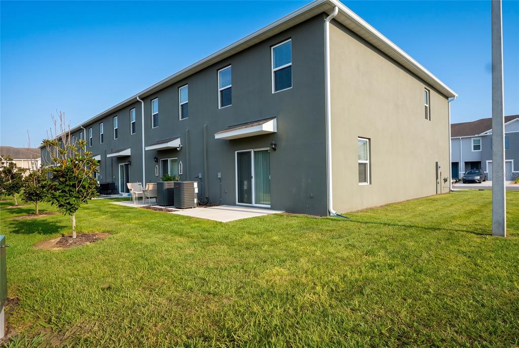 A multi-story gray townhouse exterior features a concrete patio and a small grassy yard — 2331 GIFFORD DRIVE, DAVENPORT, FL