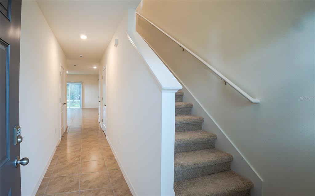 An entryway features tile flooring, a carpeted staircase with a white railing, and white walls — 2331 GIFFORD DRIVE, DAVENPORT, FL