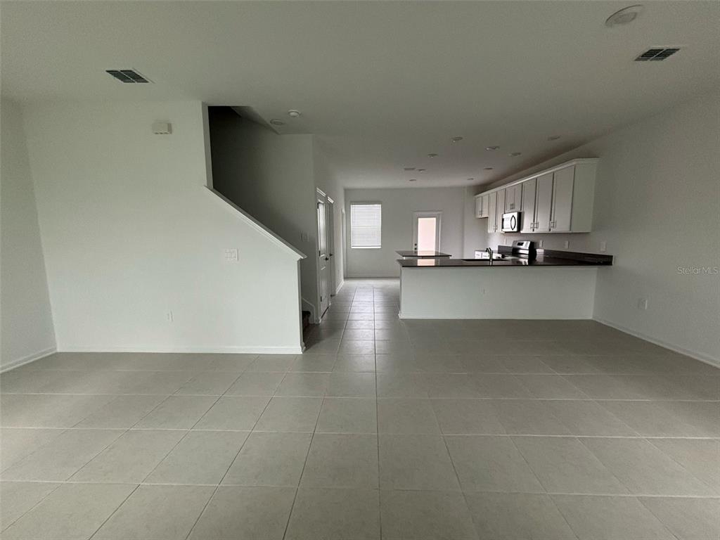 An open-concept living area features white walls, tile flooring, and a kitchen with white cabinets — 1996 TOHOQUA BOULEVARD, KISSIMMEE, FL
