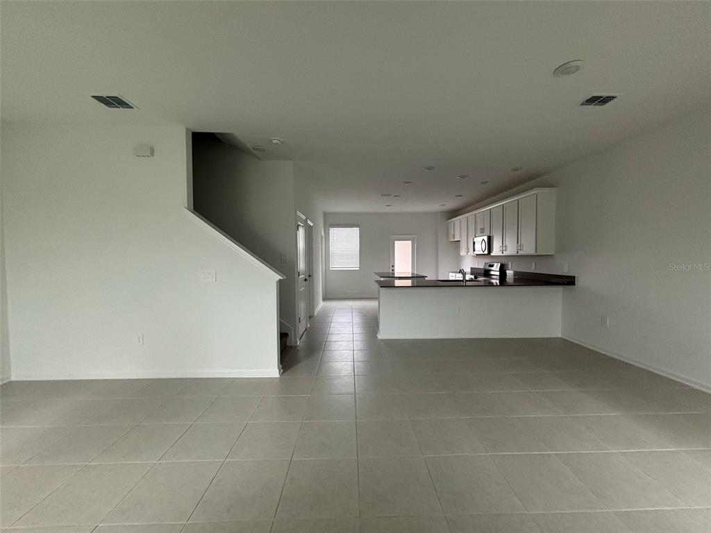 An open-concept living area features light tile flooring, a kitchen island, and white cabinetry — 1996 TOHOQUA BOULEVARD, KISSIMMEE, FL