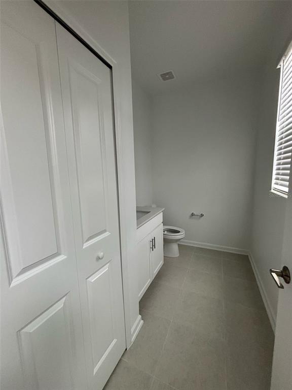 A bathroom features a white vanity, a toilet, a closet, and light-colored tile flooring — 1996 TOHOQUA BOULEVARD, KISSIMMEE, FL