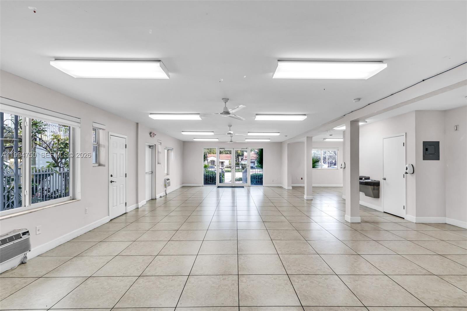 A spacious, empty room with light-colored tile flooring, recessed ceiling lights, and glass double doors — 1214 Alton Rd, Miami Beach FL 33139, MIAMI BEACH, FL