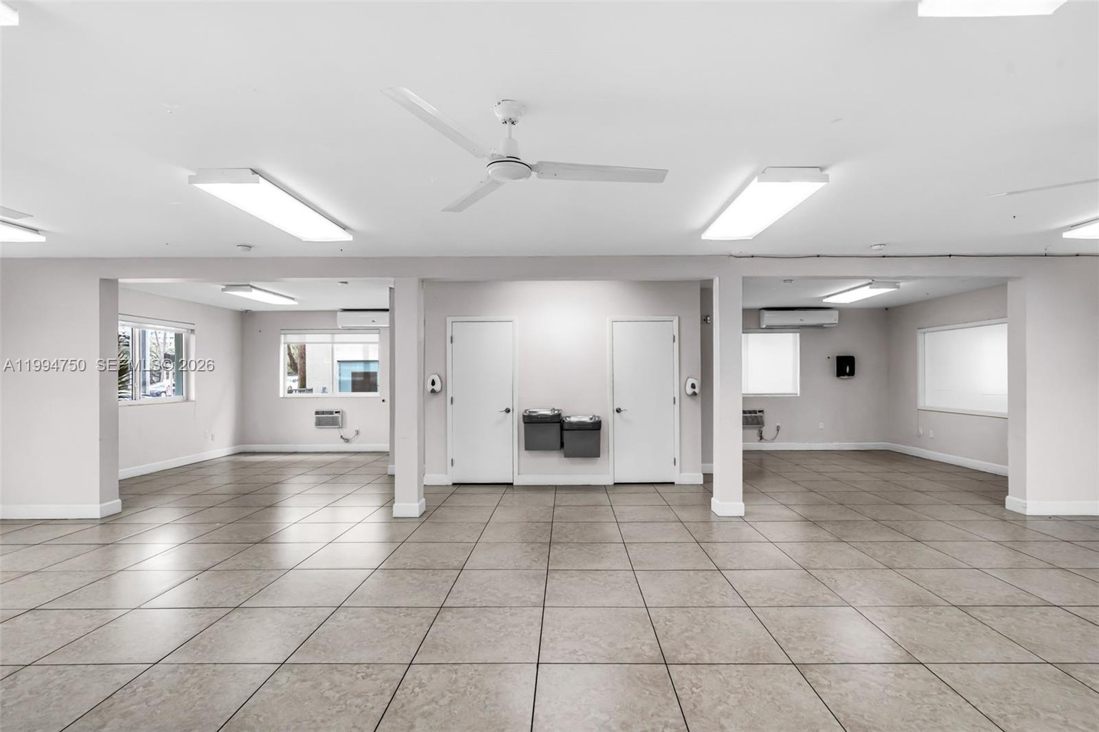 An open, tiled room features two white doors, a ceiling fan, and fluorescent lighting — 1214 Alton Rd, Miami Beach FL 33139, MIAMI BEACH, FL