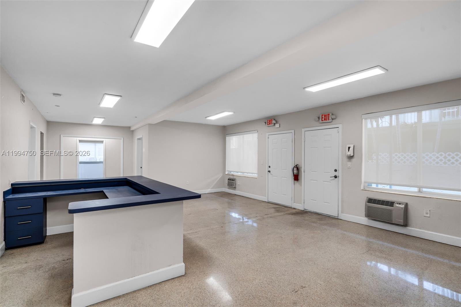 An office space features a blue reception desk, polished concrete floors, and two exit doors — 1214 Alton Rd, Miami Beach FL 33139, MIAMI BEACH, FL