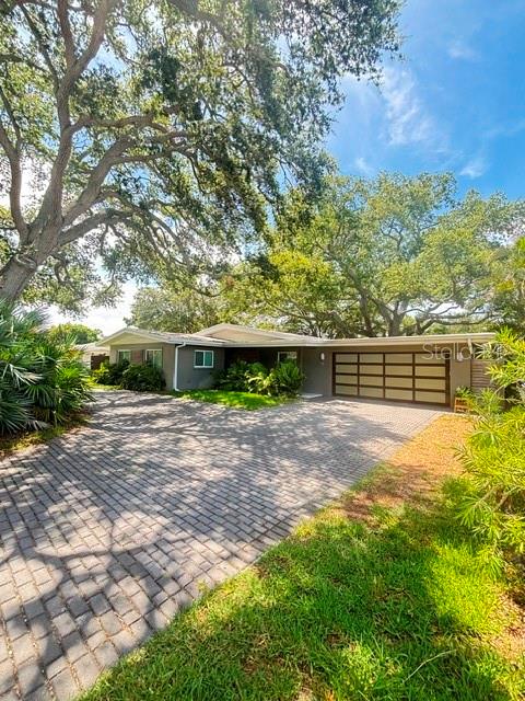 A single-story house with a paved driveway, large oak trees, and a multi-car garage — 9 SOUTHWIND DRIVE, LARGO, FL