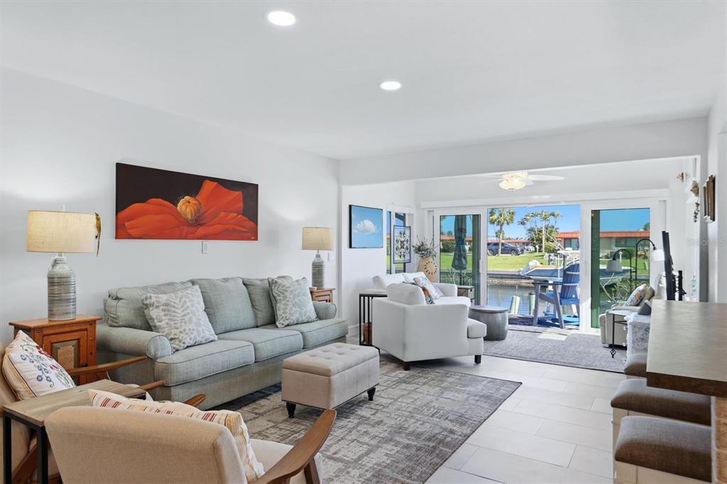 A living room with a sofa, armchairs, and sliding glass doors overlooking a canal — 9528 ANTIQUA COVE UNIT 9528, BRADENTON, FL