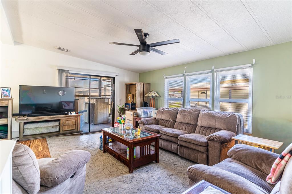 A living room features a brown sofa, a coffee table, and a television on a stand — 6450 HOLLYBERRY LANE NE, WINTER HAVEN, FL