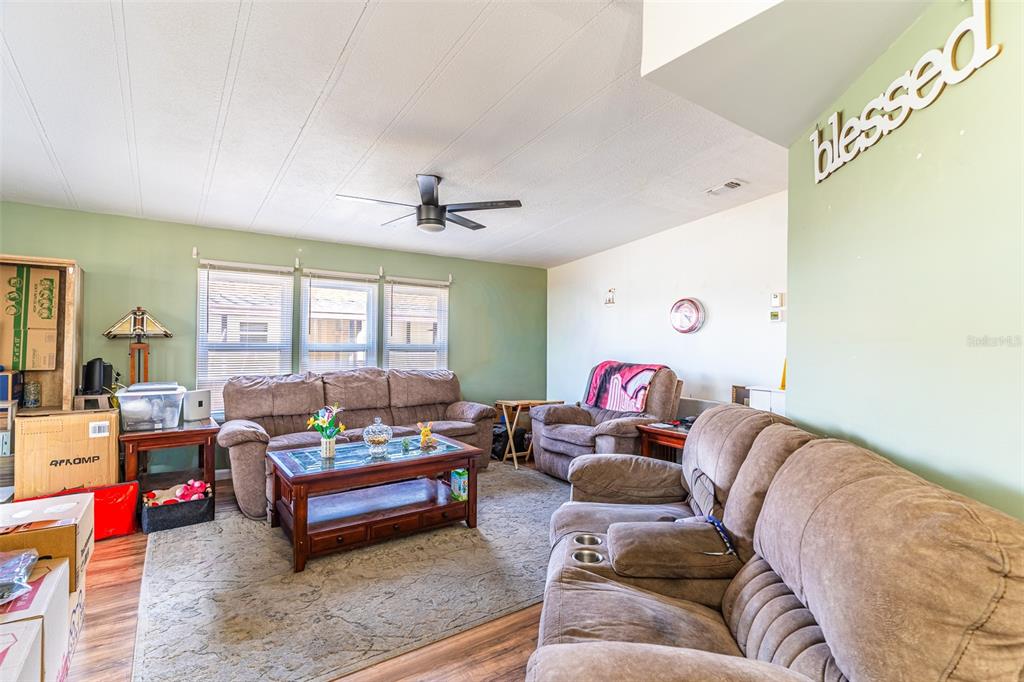 A living room features brown sofas, a coffee table, and a ceiling fan — 6450 HOLLYBERRY LANE NE, WINTER HAVEN, FL