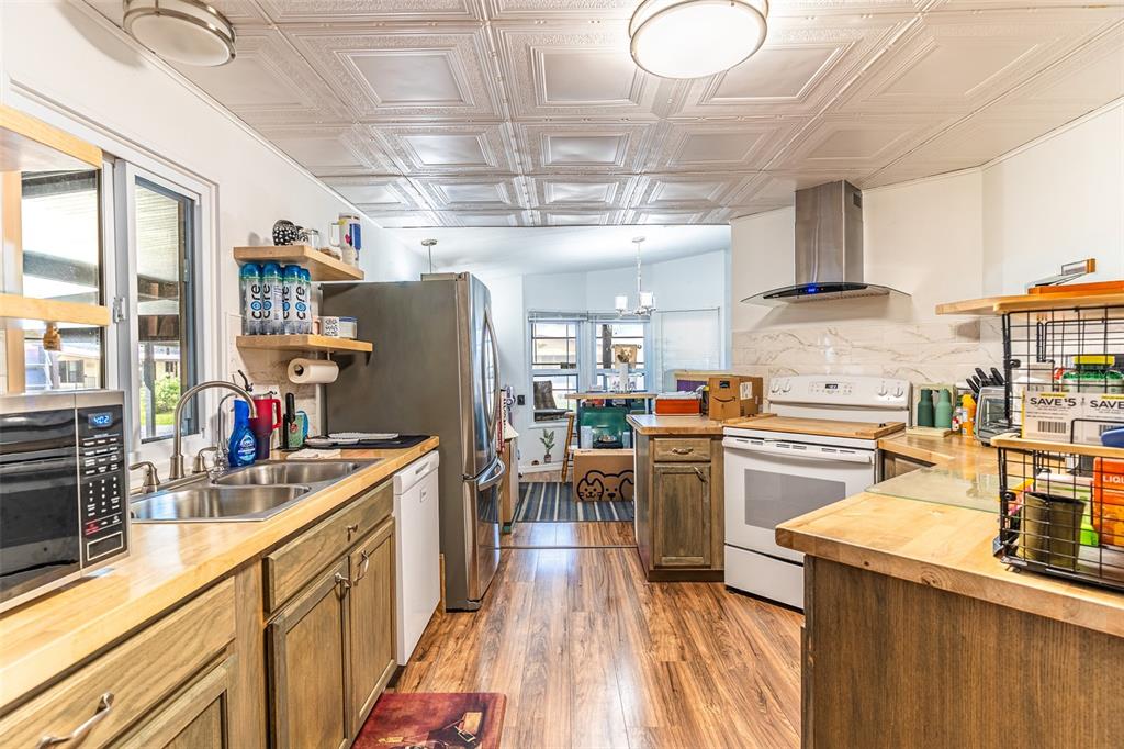 A kitchen features wood cabinets, butcher block countertops, stainless steel appliances, and a tiled ceiling — 6450 HOLLYBERRY LANE NE, WINTER HAVEN, FL