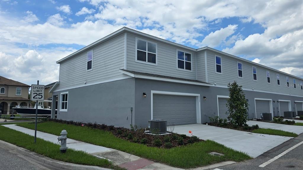 An exterior view of a multi-unit townhouse building with gray siding and concrete driveways — 3323 GRANDE HERON DRIVE, ST CLOUD, FL