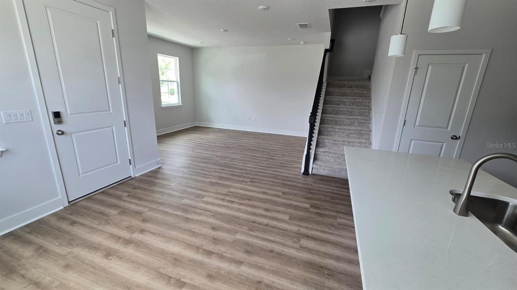 This interior view shows a kitchen island, wood-look flooring, and a staircase with carpet — 3323 GRANDE HERON DRIVE, ST CLOUD, FL