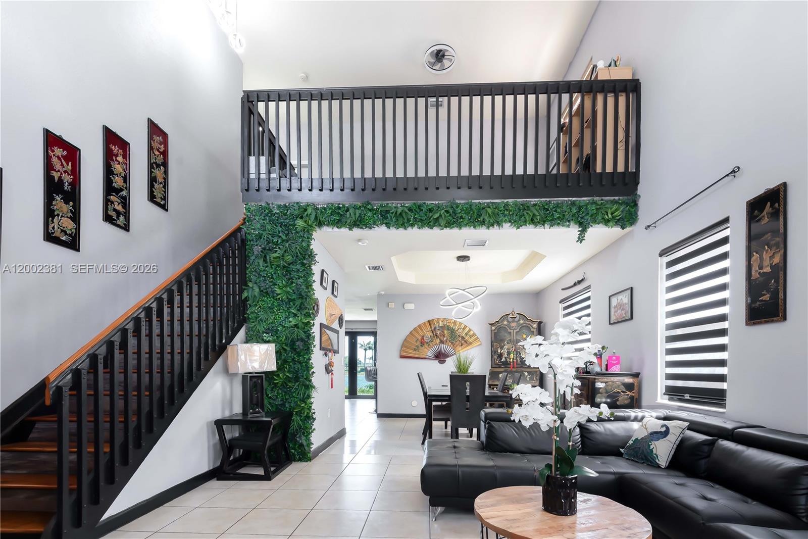 A living room features a black staircase, a loft balcony, and a green wall accent — 685 SE 37th Pl, Homestead FL 33033, HOMESTEAD, FL