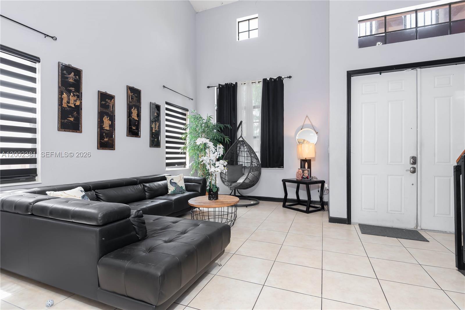 A living room features a black sectional sofa, tiled floors, and a hanging egg chair — 685 SE 37th Pl, Homestead FL 33033, HOMESTEAD, FL