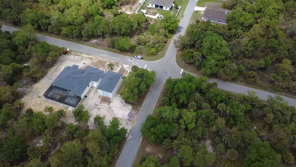 An aerial view shows a new house with a screened pool cage on a wooded lot — 18125 GARTH AVENUE, PORT CHARLOTTE, FL