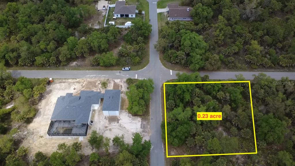 An aerial view shows a vacant, wooded residential lot outlined in yellow near a road — 18125 GARTH AVENUE, PORT CHARLOTTE, FL