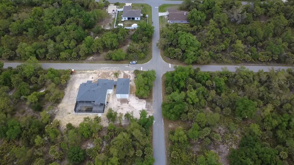 An aerial view shows a house with a pool and garage in a wooded area — 18125 GARTH AVENUE, PORT CHARLOTTE, FL