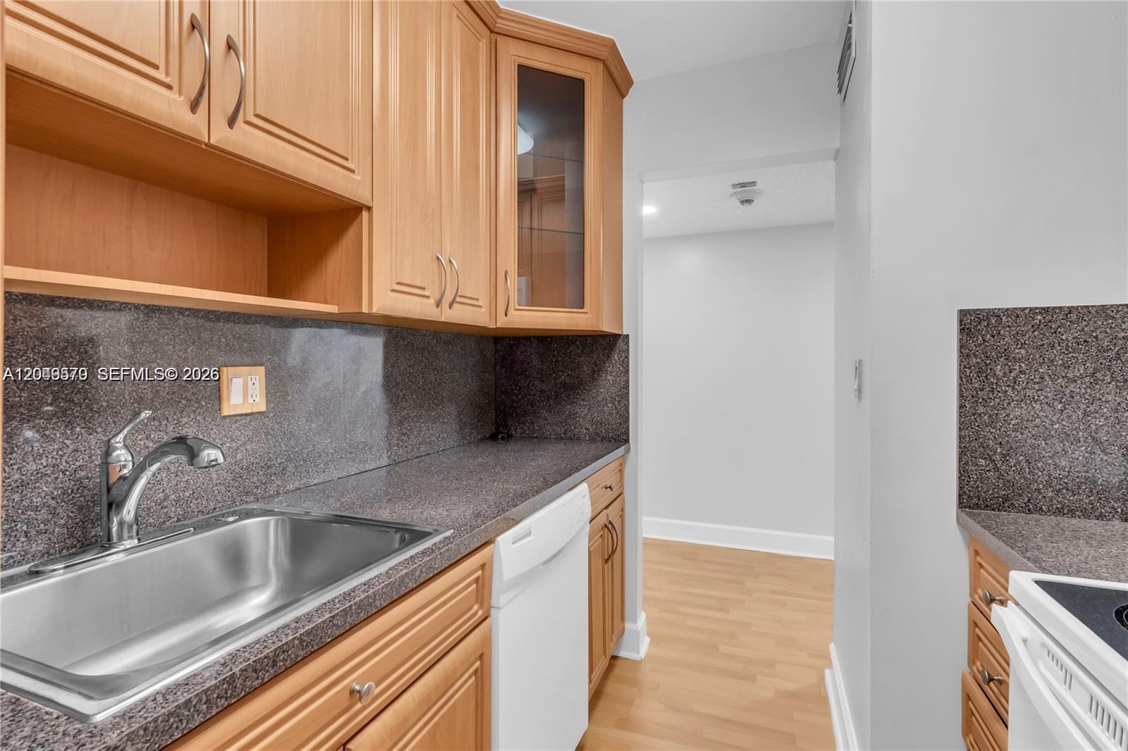 A kitchen features light wood cabinets, dark granite countertops, a stainless steel sink, and appliances — 5055 NW 7th St # 504, Miami FL 33126, MIAMI, FL