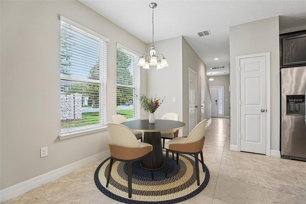 A dining area features a round table, four chairs, a chandelier, and tile flooring — 198 MITCHELL CREEK WAY, OVIEDO, FL
