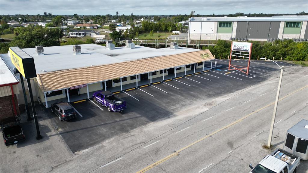 An aerial view shows a commercial strip mall with a parking lot and signage — 3527 TAMIAMI TRAIL UNIT E, PORT CHARLOTTE, FL