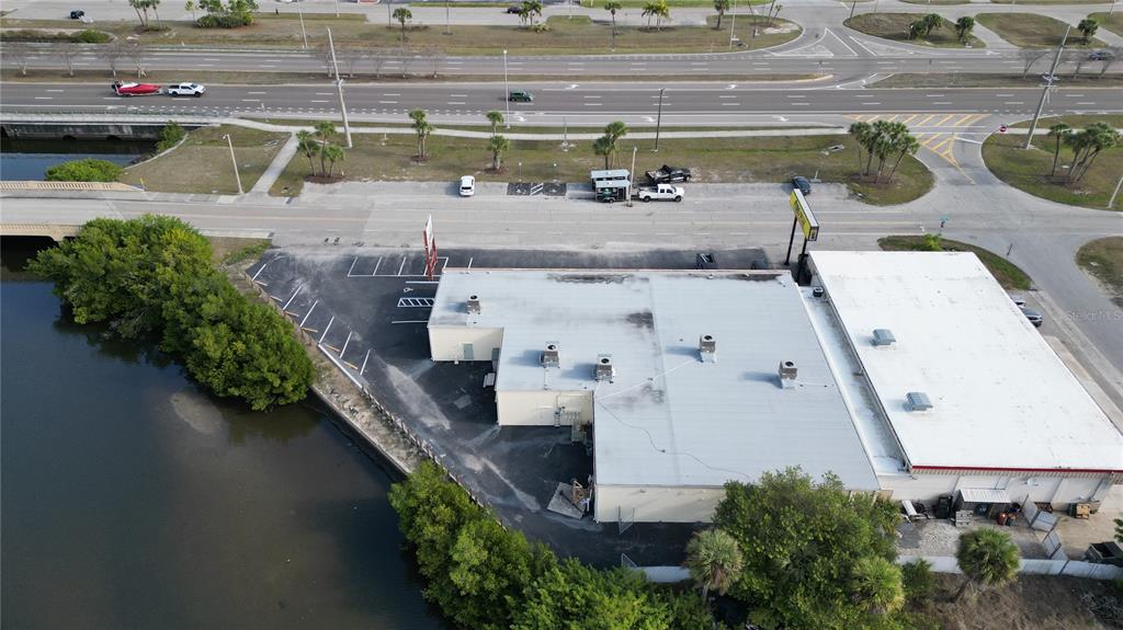 An aerial view shows a commercial building with a flat roof next to a waterway — 3527 TAMIAMI TRAIL UNIT E, PORT CHARLOTTE, FL