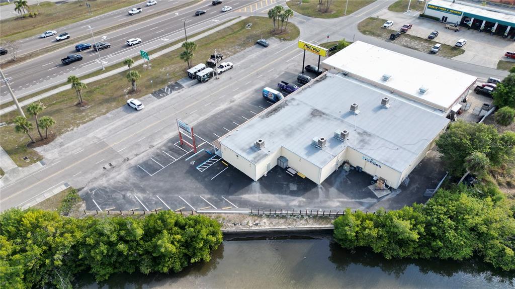An aerial view shows a commercial building with a parking lot next to a waterway — 3527 TAMIAMI TRAIL UNIT E, PORT CHARLOTTE, FL