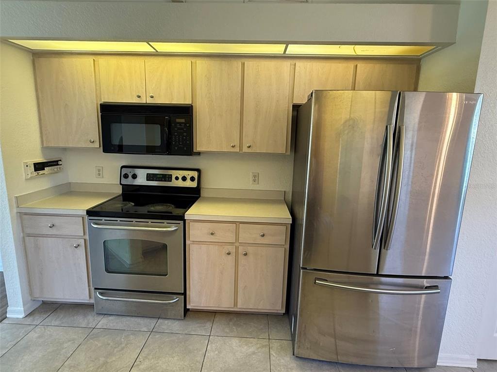 A kitchen features light wood cabinets, stainless steel appliances, and tile flooring — 4054 ALLURE LANE, NORTH PORT, FL