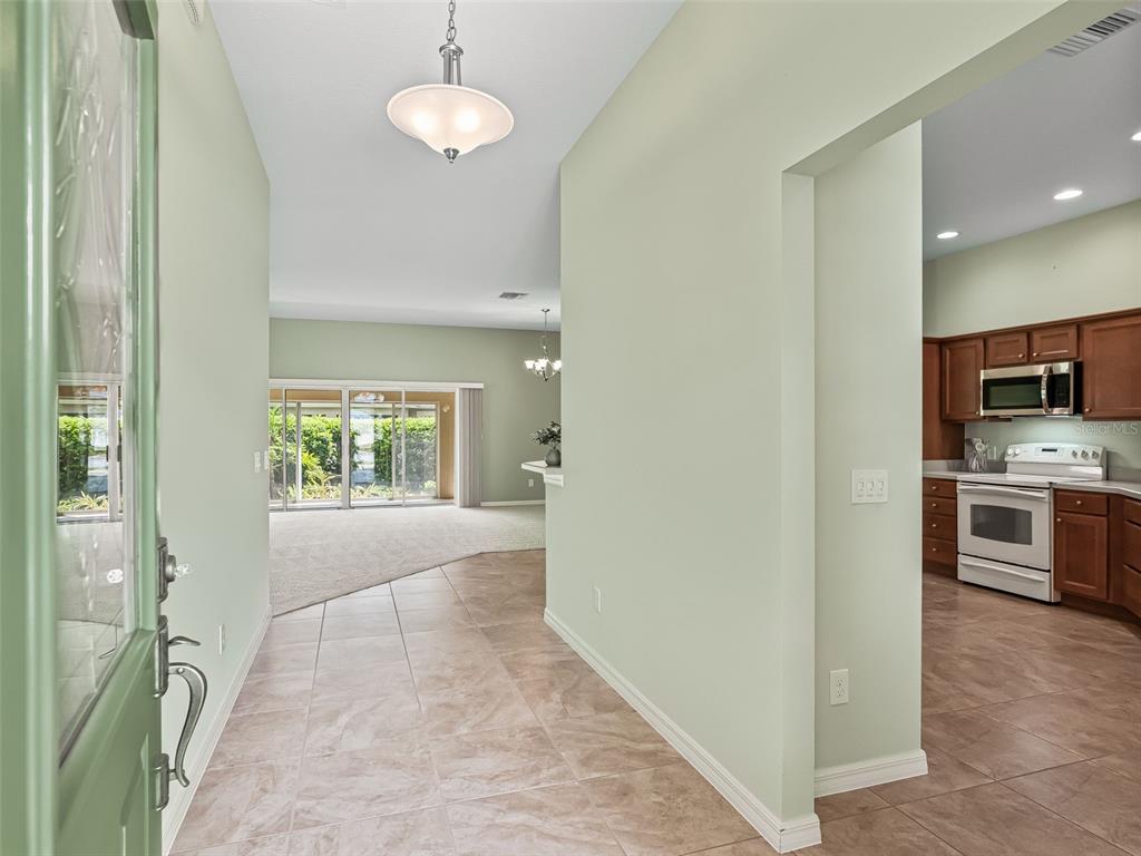 An entryway with tile flooring leads to a living area and an adjacent kitchen — 2215 TRIGGERFISH RUN, THE VILLAGES, FL