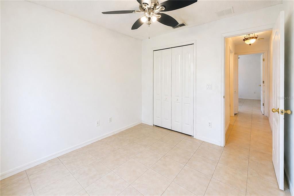 A bedroom with white walls, tile flooring, a ceiling fan, and a white closet door — 2281 OAKINGTON STREET, WINTER GARDEN, FL
