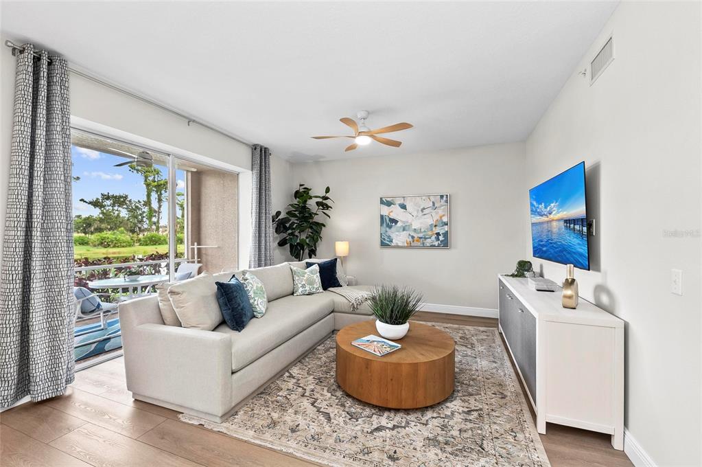 A living room features a sectional sofa, round coffee table, media console, and sliding glass doors — 5280 HYLAND HILLS AVENUE UNIT 1812, SARASOTA, FL
