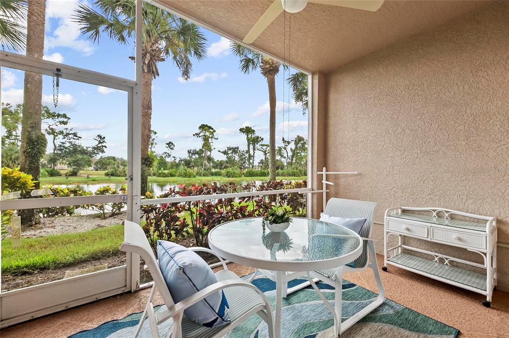 A screened-in patio features a glass-topped table, chairs, and a view of a lake — 5280 HYLAND HILLS AVENUE UNIT 1812, SARASOTA, FL