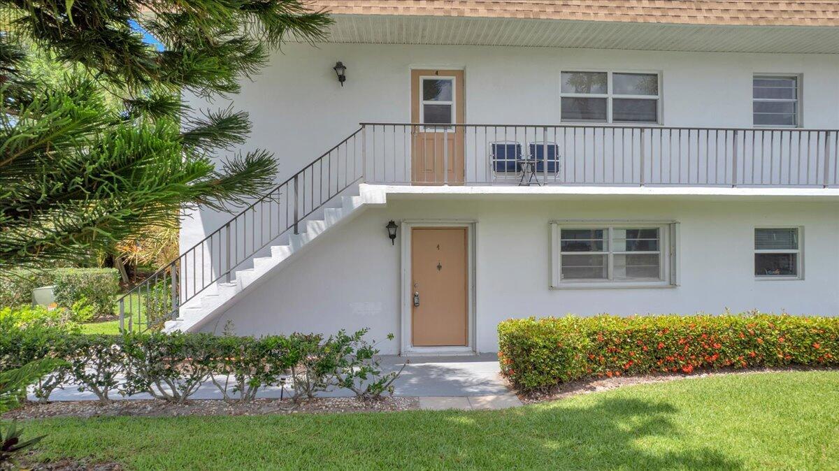A two-story white apartment building features an exterior staircase leading to an upper-level unit — 2950 SE Ocean Boulevard # 1, Stuart FL 34996, STUART, FL