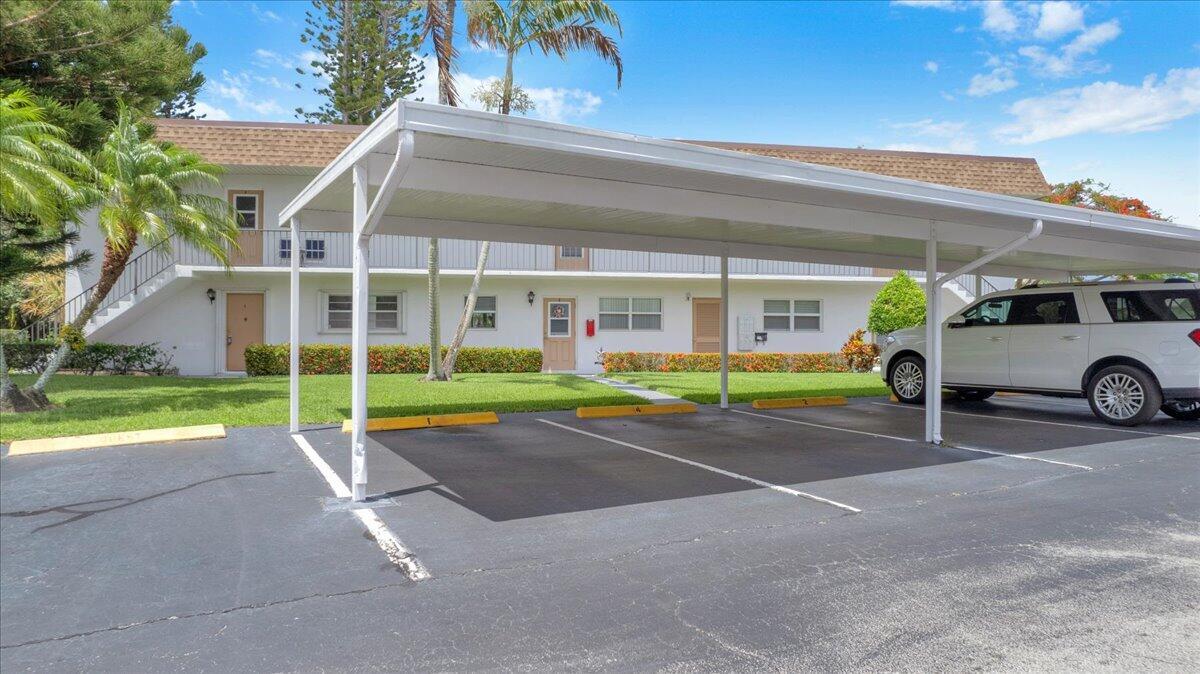 A two-story apartment building exterior features a covered parking area with marked spaces — 2950 SE Ocean Boulevard # 1, Stuart FL 34996, STUART, FL