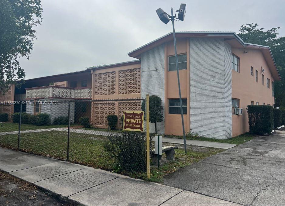 A two-story peach-colored apartment building features decorative concrete blocks and a chain-link fence — 19080 NE 3rd Ct # 312, Miami FL 33179, MIAMI, FL