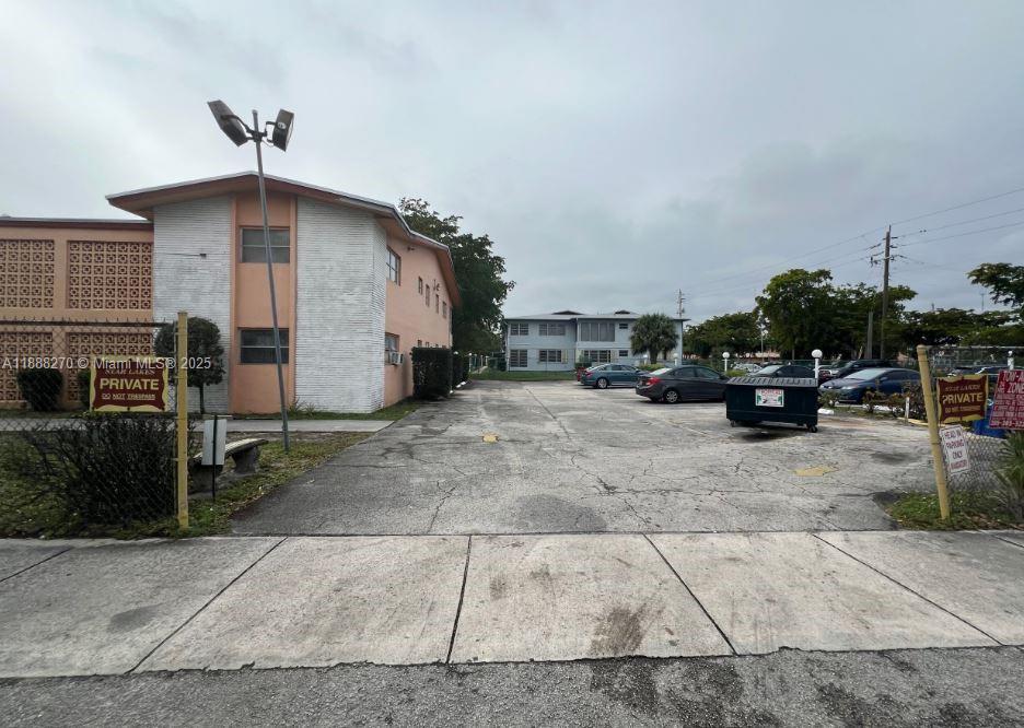 A two-story apartment building stands next to a paved parking lot with a dumpster — 19080 NE 3rd Ct # 312, Miami FL 33179, MIAMI, FL