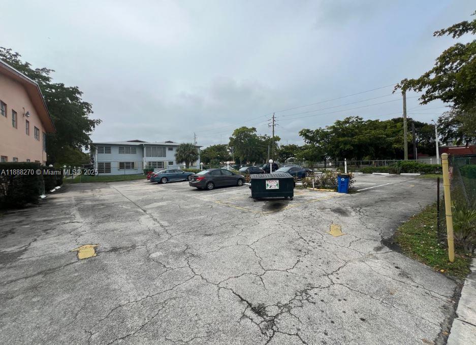 A paved parking lot with a dumpster sits in front of a multi-story apartment building — 19080 NE 3rd Ct # 312, Miami FL 33179, MIAMI, FL