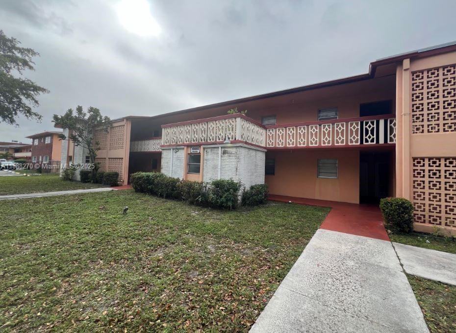 A two-story peach-colored apartment building with decorative concrete screens and a concrete walkway — 19080 NE 3rd Ct # 312, Miami FL 33179, MIAMI, FL