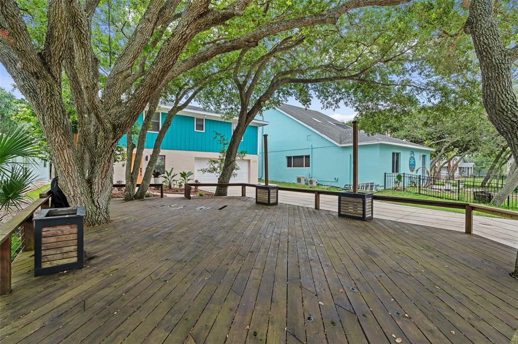 A large wooden deck features built-in planters and mature trees in a residential backyard — 1339 S DAYTONA AVENUE, FLAGLER BEACH, FL