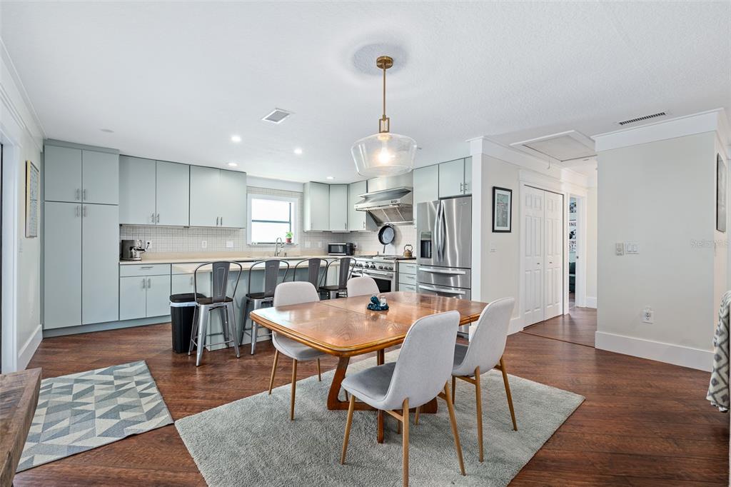 A kitchen and dining area feature light blue cabinets, stainless steel appliances, and wood flooring — 1339 S DAYTONA AVENUE, FLAGLER BEACH, FL