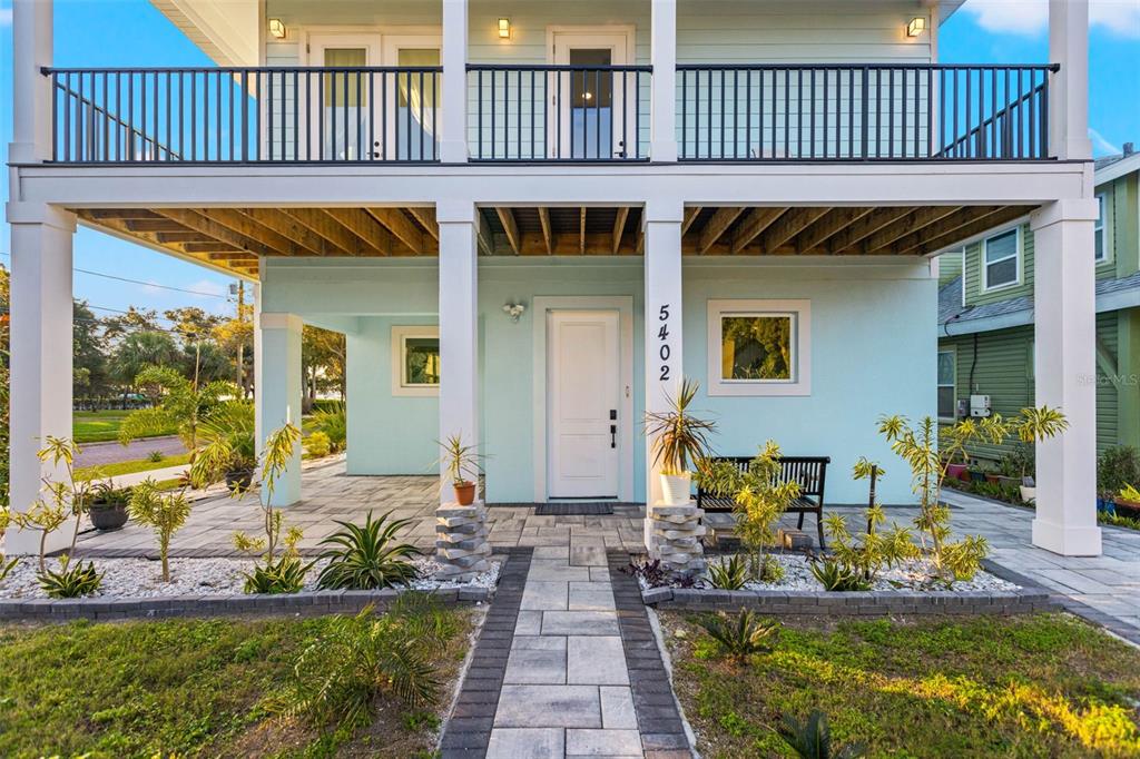 A light blue two-story house with a covered ground-level patio and a second-floor balcony — 5402 31ST AVENUE S, GULFPORT, FL