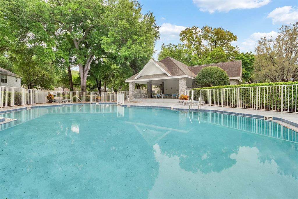 A swimming pool sits in front of a covered outdoor pavilion surrounded by trees — 930 LOCH CARRON UNIT 1212, APOPKA, FL