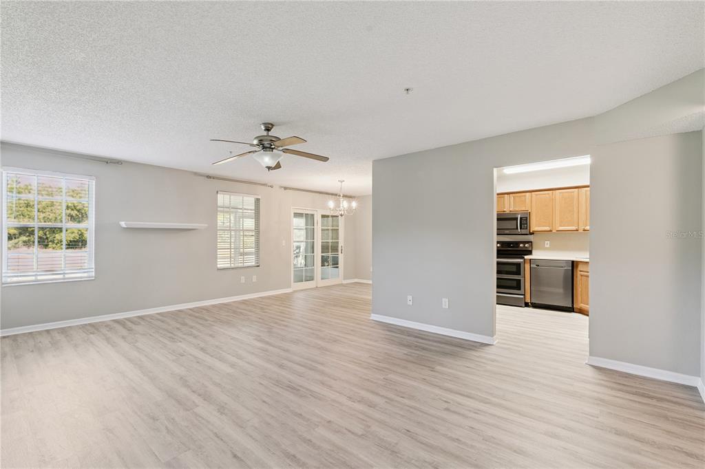 An open-concept living area with light wood-look flooring, a ceiling fan, and an adjacent kitchen — 930 LOCH CARRON UNIT 1212, APOPKA, FL