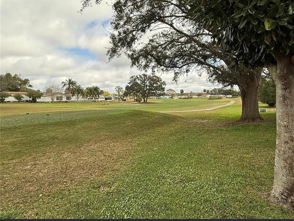 A view of a grassy golf course fairway with mature trees and distant houses — 1532 W SCHWARTZ BOULEVARD, LADY LAKE, FL