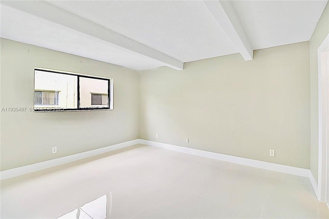 An empty room features white tile flooring, light-colored walls, and a window with white trim — 1065 S Flagler Ave # 701, Pompano Beach FL 33060, POMPANO BEACH, FL