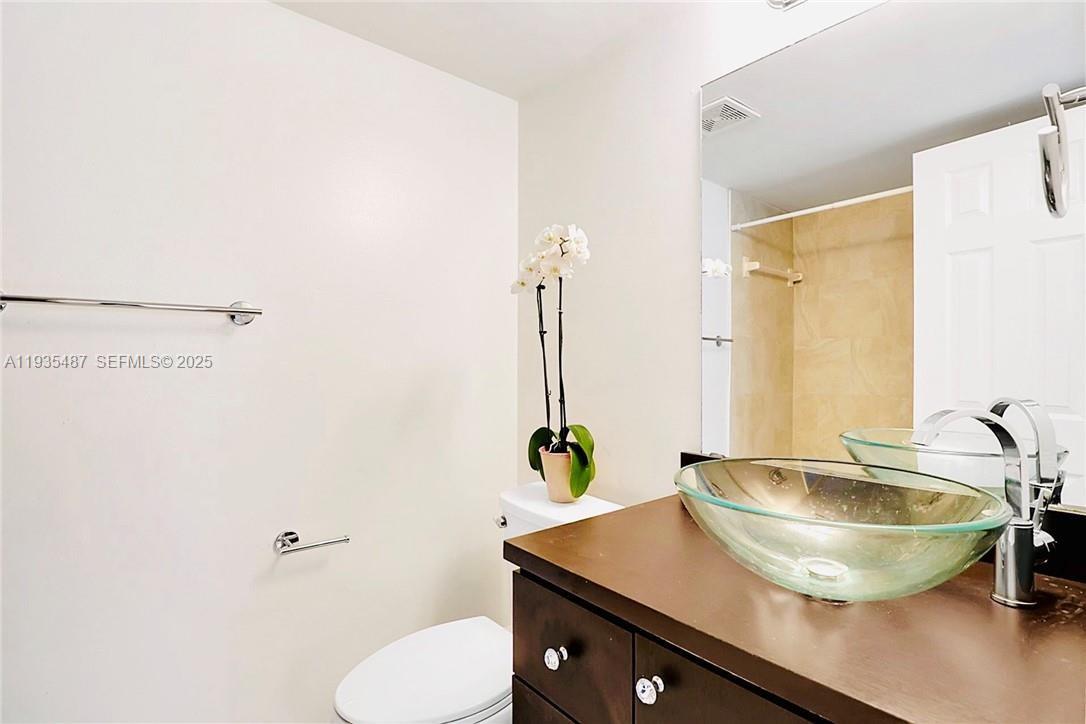 A bathroom features a dark wood vanity, a glass vessel sink, and a toilet — 1065 S Flagler Ave # 701, Pompano Beach FL 33060, POMPANO BEACH, FL
